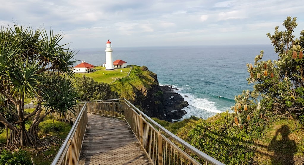 Cape Byron Lighthouse white tower with red-capped dome on green grassy headland above basalt cliffs NSW