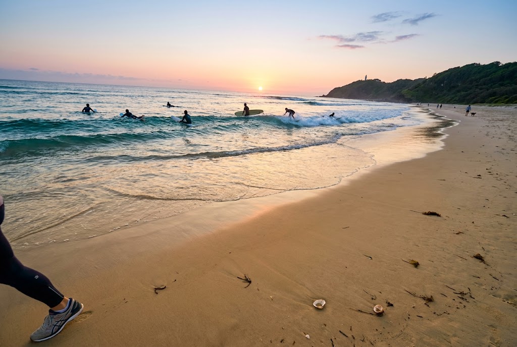Byron Bay surf morning: surfers on Main Beach at dawn with rising sun over Pacific horizon